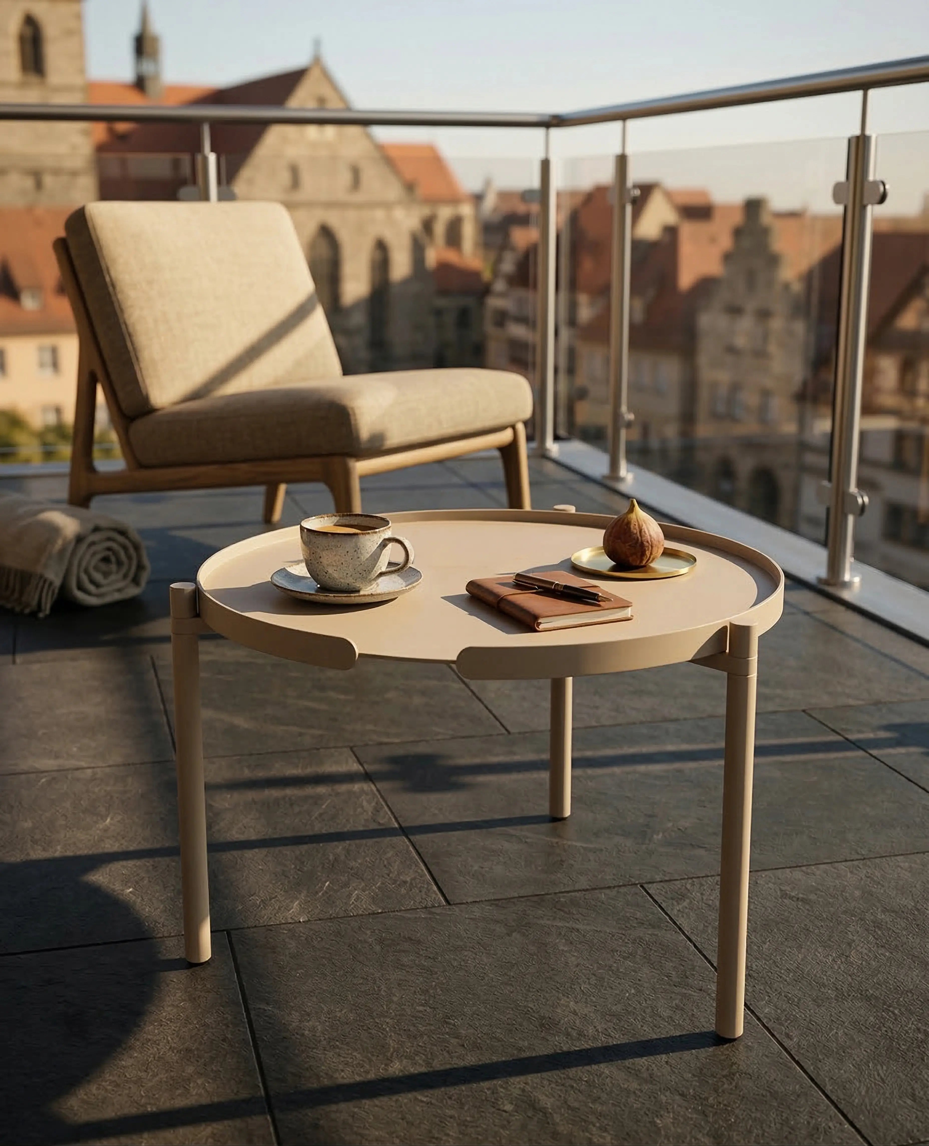 Runder Couchtisch ORBIS von Siqual Design in Beige auf einer Dachterrasse vor einem hellen Sessel – wetterfester Outdoor-Tisch aus pulverbeschichtetem Aluminium.