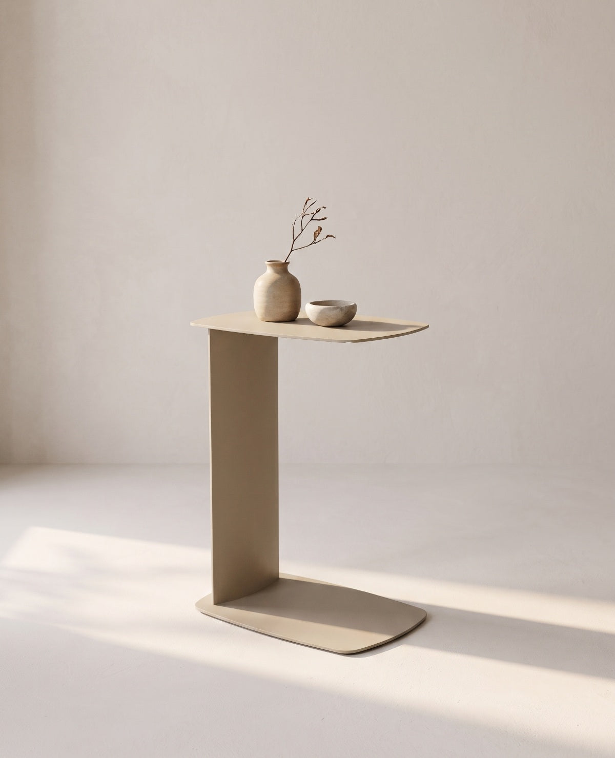 Beiger STANDBY Beistelltisch in C-Form aus Metall von Siqual Design mit Vase und Schale im hellen Wohnraum