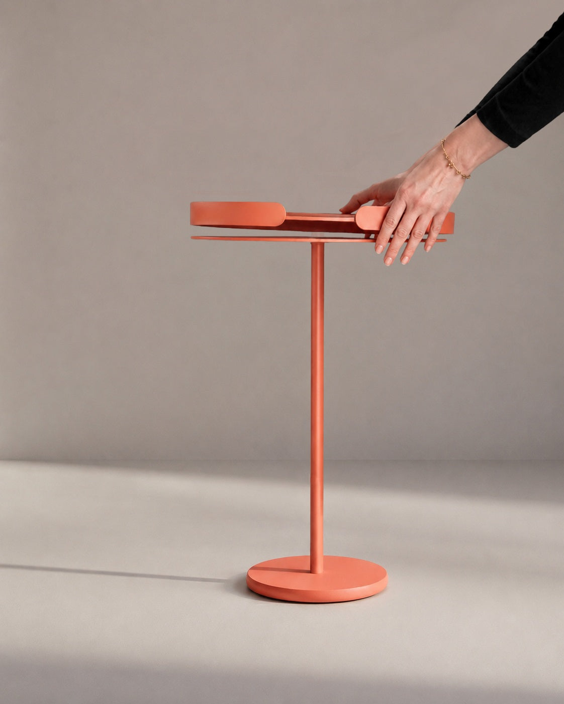 Hände nehmen das abnehmbare Tablett vom OLLIE Beistelltisch aus Metall und zeigen die flexible Nutzung.