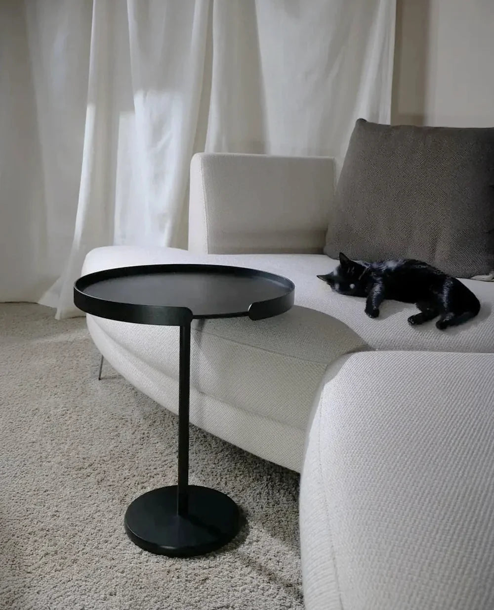 Ollie Tisch steht am Sofa und ragt mit dem Tablett über die Sitzfläche