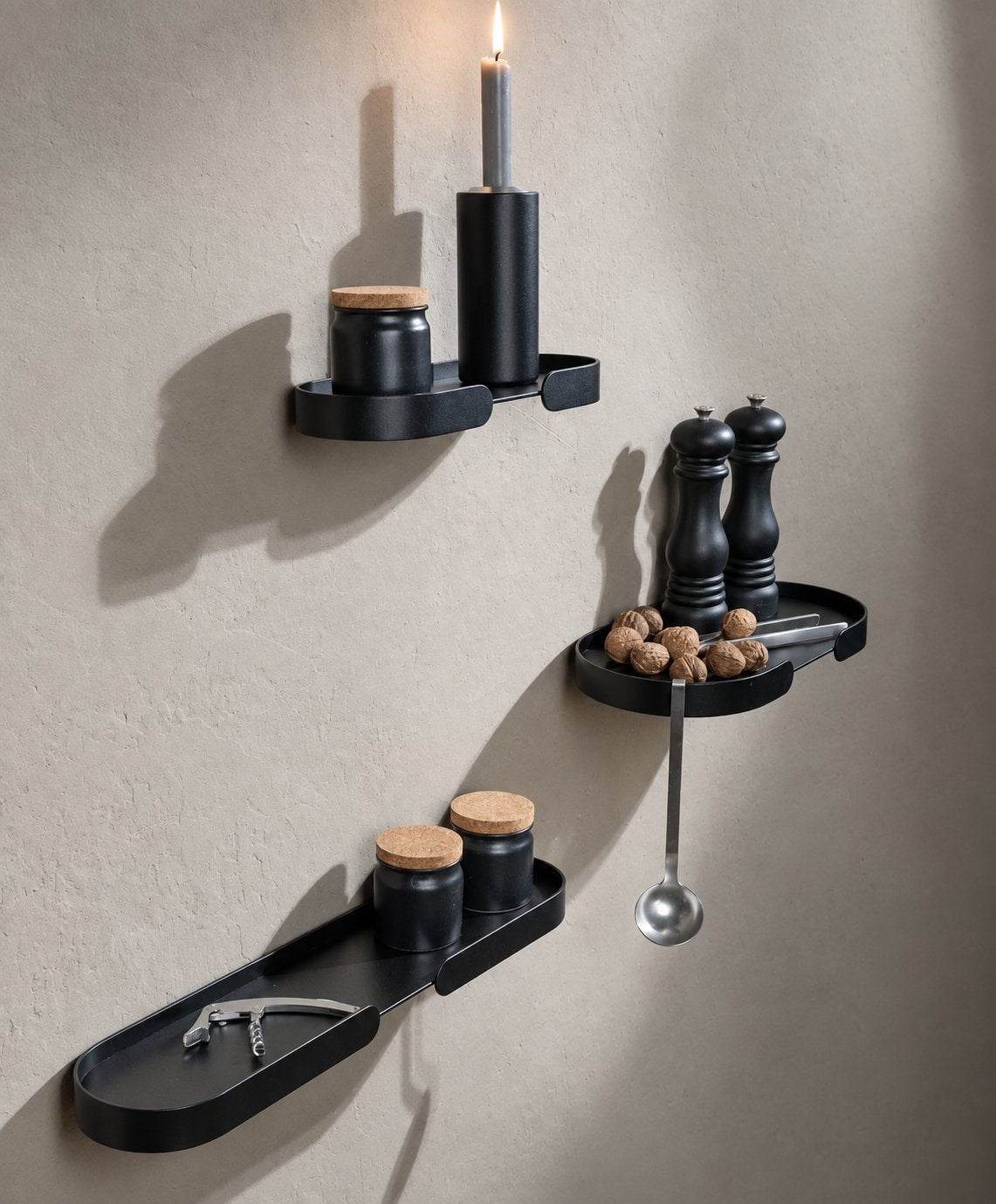 Schwarze Design-Wandregale aus pulverbeschichtetem Aluminium von Siqual Design in der Küche – mit Gewürzen, Kerze und Küchenutensilien als platzsparende Wandablage.