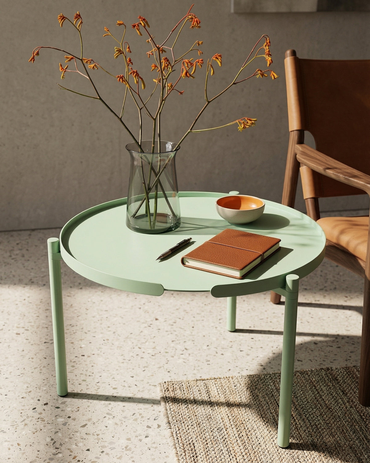 Runder Couchtisch ORBIS aus Metall in Mint von Siqual Design auf Terrazzoboden mit Vase und Notizbuch