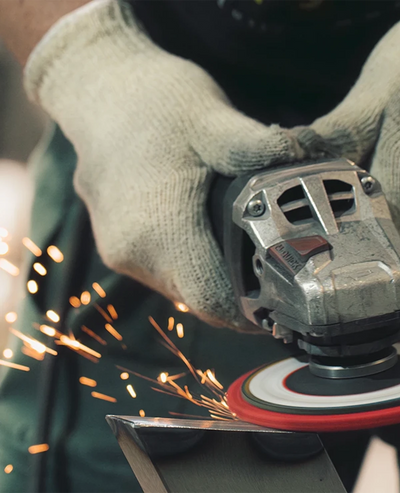 Hände bei der Metallbearbeitung mit sprühenden Funken in der Siqual Design Manufaktur