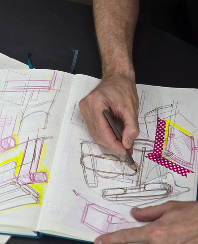 Designer skizziert in seinem Skizzenbuch und entwicklet neue Ideen für Siqual Design.
