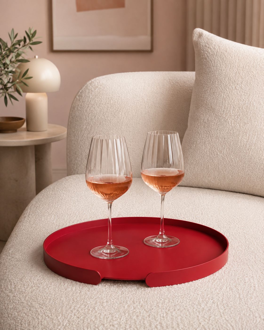 Rotes rundes LILO Tablett von Siqual Design mit zwei Roségläsern auf weißem Bouclé-Sofa in modernem Wohnambiente.