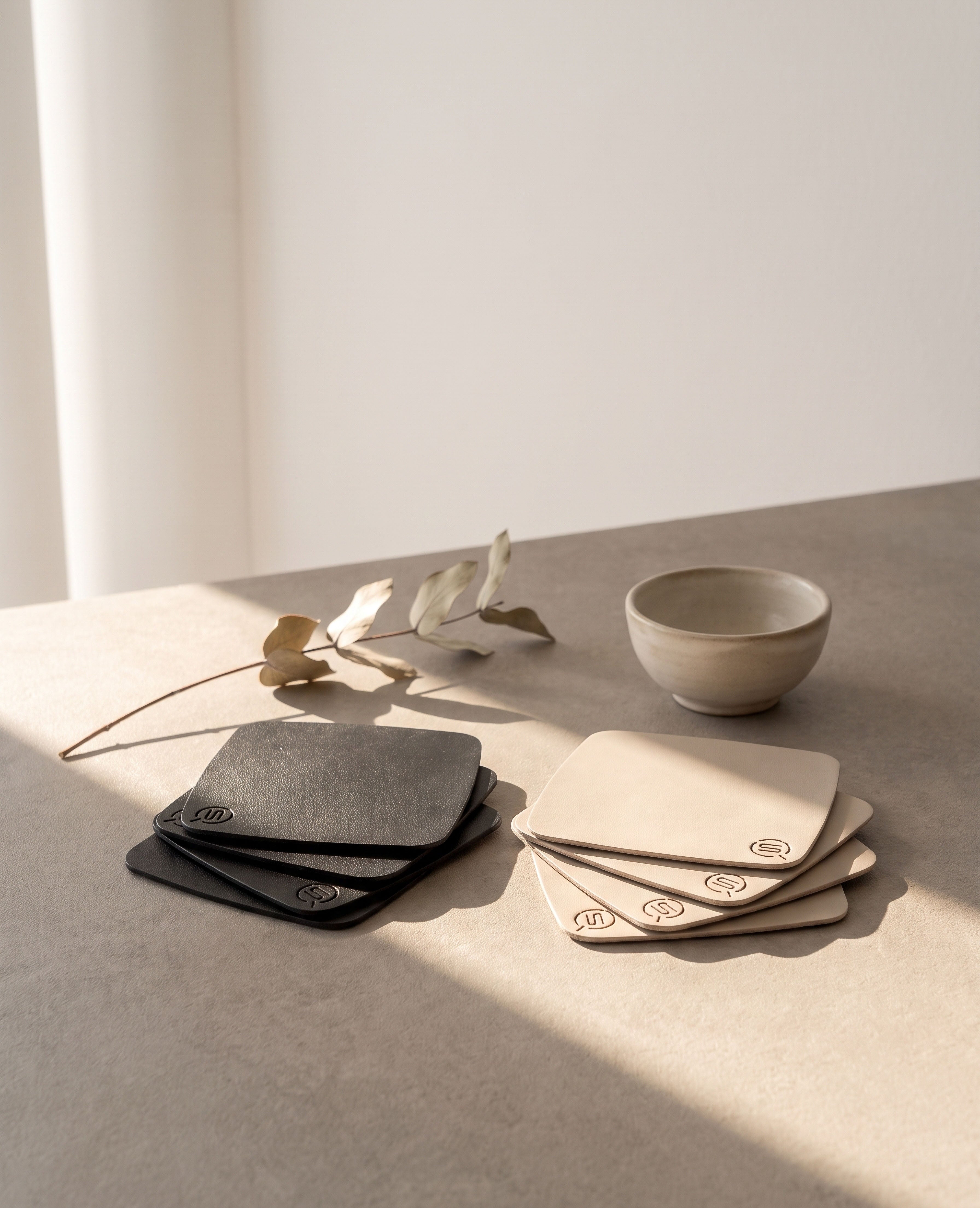 Schwarze und beige PLAZA Design-Untersetzer aus Edelstahl von Siqual Design im 4er-Set mit matt pulverbeschichteter Oberfläche für moderne Tischkultur im Innen- und Außenbereich.